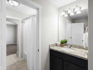 Bathroom with tile flooring, shower / bath combination with curtain, and vanity