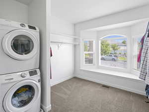 Washroom with stacked washer / dryer and carpet floors