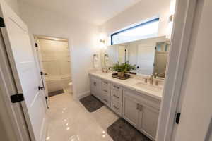 Full bathroom with tile flooring, shower / washtub combination, large vanity, toilet, and dual sinks