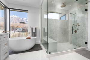 Bathroom featuring separate shower and tub, vanity, and tile floors