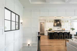 Living room with beamed ceiling, light wood-type flooring, and crown molding