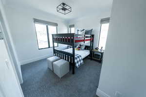 Carpeted bedroom with crown molding and multiple windows