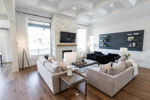 Living room with crown molding, hardwood / wood-style floors, beam ceiling, a fireplace, and coffered ceiling