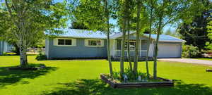 Ranch-style house featuring a garage, a front yard, and a porch