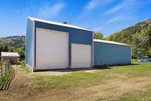 View of outdoor structure with a garage and a lawn