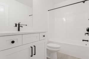 Full bathroom with washtub / shower combination, hardwood / wood-style floors, vanity, and toilet