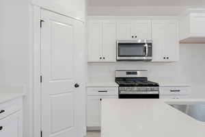 Kitchen with white cabinetry, sink, stainless steel appliances, and light hardwood / wood-style flooring