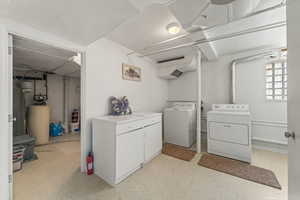 Laundry room with washer and dryer, cabinets, and light flooring.