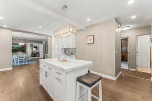 Kitchen featuring wood-type flooring, white cabinets, a center island, and pendant lighting