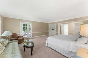 Bedroom with carpet floors, crown molding, french doors, and access to outside balcony.