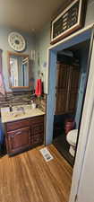 Bathroom with hardwood / wood-style flooring, vanity, toilet, and decorative backsplash