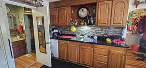 Kitchen featuring dishwasher, sink, light hardwood / wood-style flooring, and backsplash