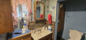 Bathroom with vanity with extensive cabinet space, backsplash, and toilet