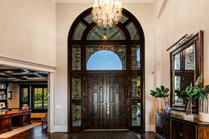 Foyer with an inviting chandelier, dark hardwood / wood-style flooring, coffered ceiling, and crown molding