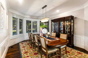 Dining space featuring a healthy amount of sunlight, dark wood-type flooring, a notable chandelier, and ornamental molding