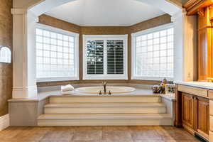 Bathroom with tile floors, a washtub, a healthy amount of sunlight, and vanity