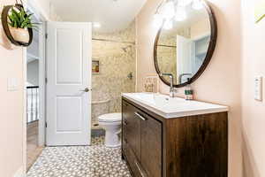 Bathroom with tile flooring, tiled shower, oversized vanity, and toilet