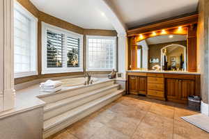 Bathroom featuring double vanity, tile flooring, decorative columns, and a washtub