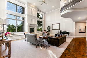 Living room featuring a towering ceiling, hardwood / wood-style flooring, ornamental molding, and ceiling fan