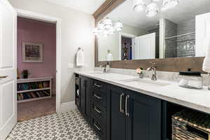 Bathroom featuring a notable chandelier, tile flooring, oversized vanity, and double sink