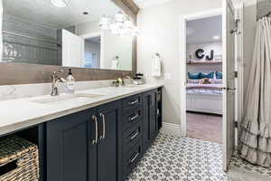 Bathroom with tile floors, a textured ceiling, oversized vanity, and double sink