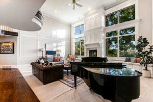 Living room with a towering ceiling, ceiling fan, light hardwood / wood-style floors, and ornamental molding