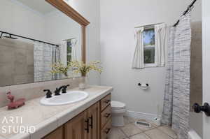 Full bathroom featuring tile flooring, ornamental molding, shower / tub combo, vanity, and toilet