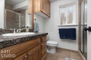 Bathroom featuring an enclosed shower, tile flooring, large vanity, and toilet