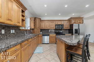 2nd Kitchen featuring backsplash, a breakfast bar area, appliances with stainless steel finishes, sink, and light tile floors