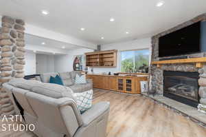 Living room featuring a stone fireplace and light wood-type flooring