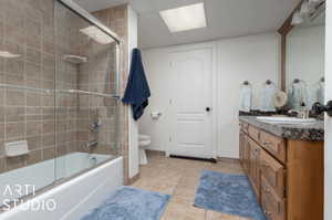 Full bathroom featuring shower / bath combination with glass door, tile flooring, vanity, and toilet