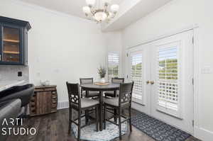 Dining area featuring dark hardwood / wood-style floors, ornamental molding, an inviting chandelier, and french doors