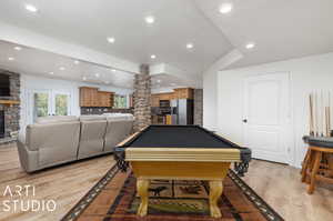 Rec room with light hardwood / wood-style floors, vaulted ceiling, a fireplace, a textured ceiling, and billiards