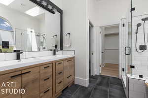 Remodeled Bathroom with tile floors, a shower with shower door, a skylight, and dual vanity