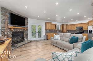 Living room featuring french doors open to covered patio, light hardwood / wood-style floors, and a fireplace