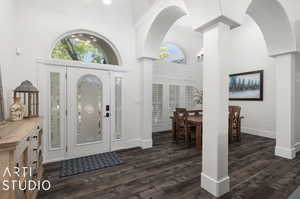 Foyer entrance featuring a towering ceiling, LVP flooring, and decorative columns