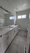 Bathroom with vanity with extensive cabinet space and toilet