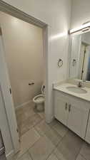 Bathroom with toilet, tile floors, and large vanity