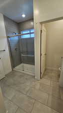 Bathroom featuring an enclosed shower, toilet, and tile floors