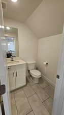 Bathroom with tile flooring, oversized vanity, lofted ceiling, and toilet