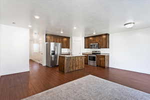 Kitchen featuring dark brown cabinets, stainless steel appliances, a center island with sink, dark hardwood / wood-style flooring, and sink