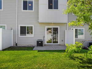 Back of property with a patio area, central AC unit, and a yard