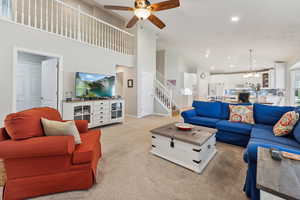 Carpeted living room with ceiling fan and a towering ceiling