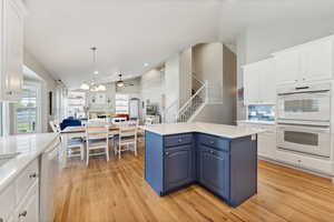 Kitchen with double oven, blue cabinets, light hardwood / wood-style floors, and white cabinets