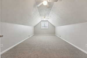 Additional living space with ceiling fan, vaulted ceiling, a textured ceiling, and carpet flooring