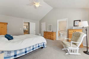 Carpeted bedroom featuring high vaulted ceiling, ceiling fan, and ensuite bath