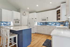 Kitchen with light hardwood / wood-style floors, white appliances, sink, tasteful backsplash, and vaulted ceiling