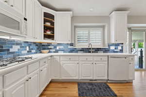 Kitchen featuring white cabinets, white appliances, and light hardwood / wood-style flooring