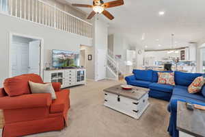 Carpeted living room featuring high vaulted ceiling and ceiling fan