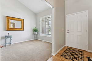 Carpeted entryway featuring lofted ceiling